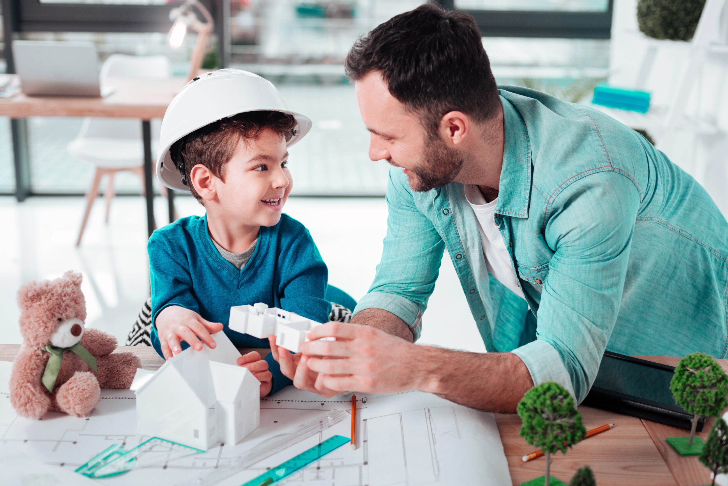 A father and a son wearing a helmet are building a model together.